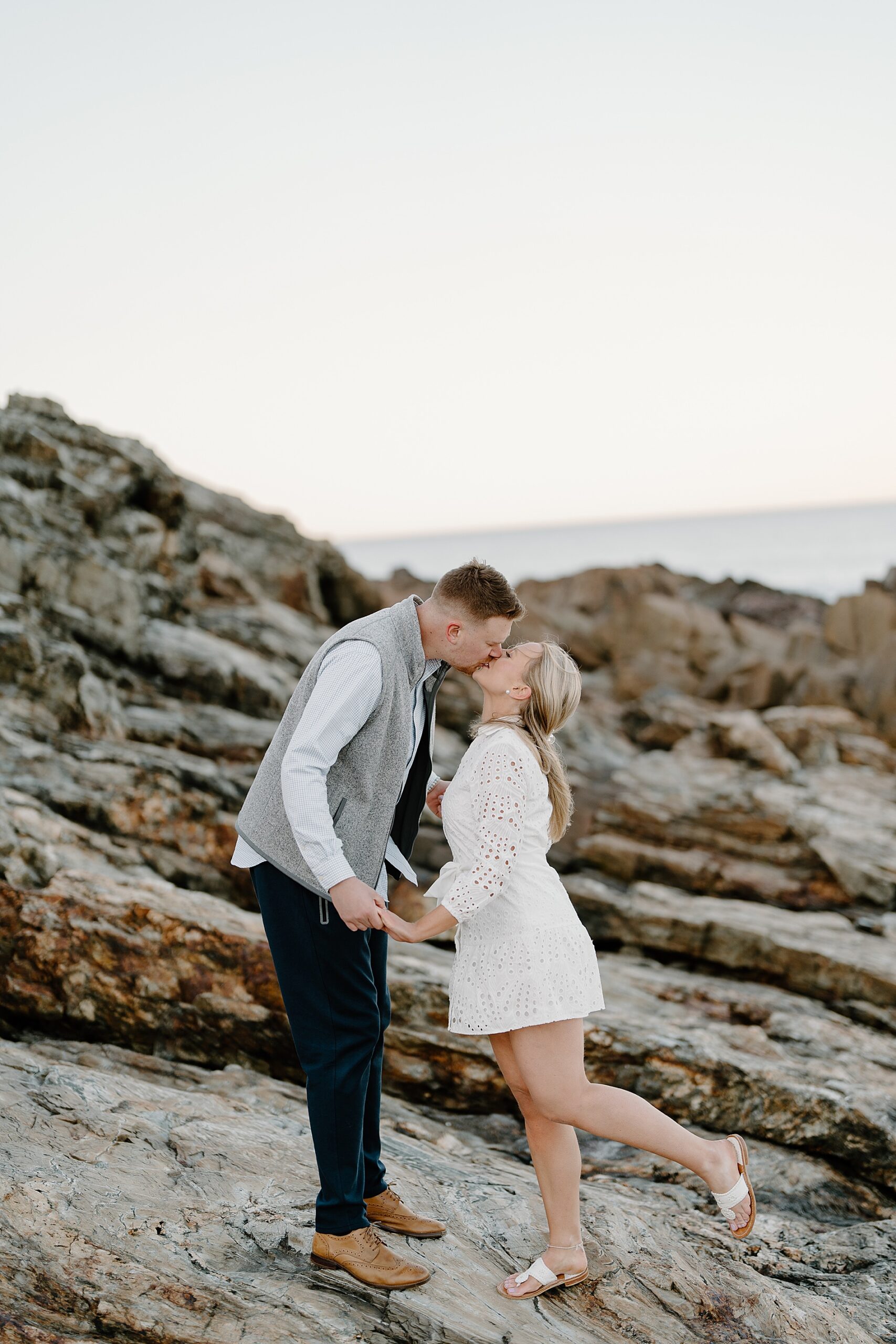 couple kiss on the rocky cliffs on a Maine beach