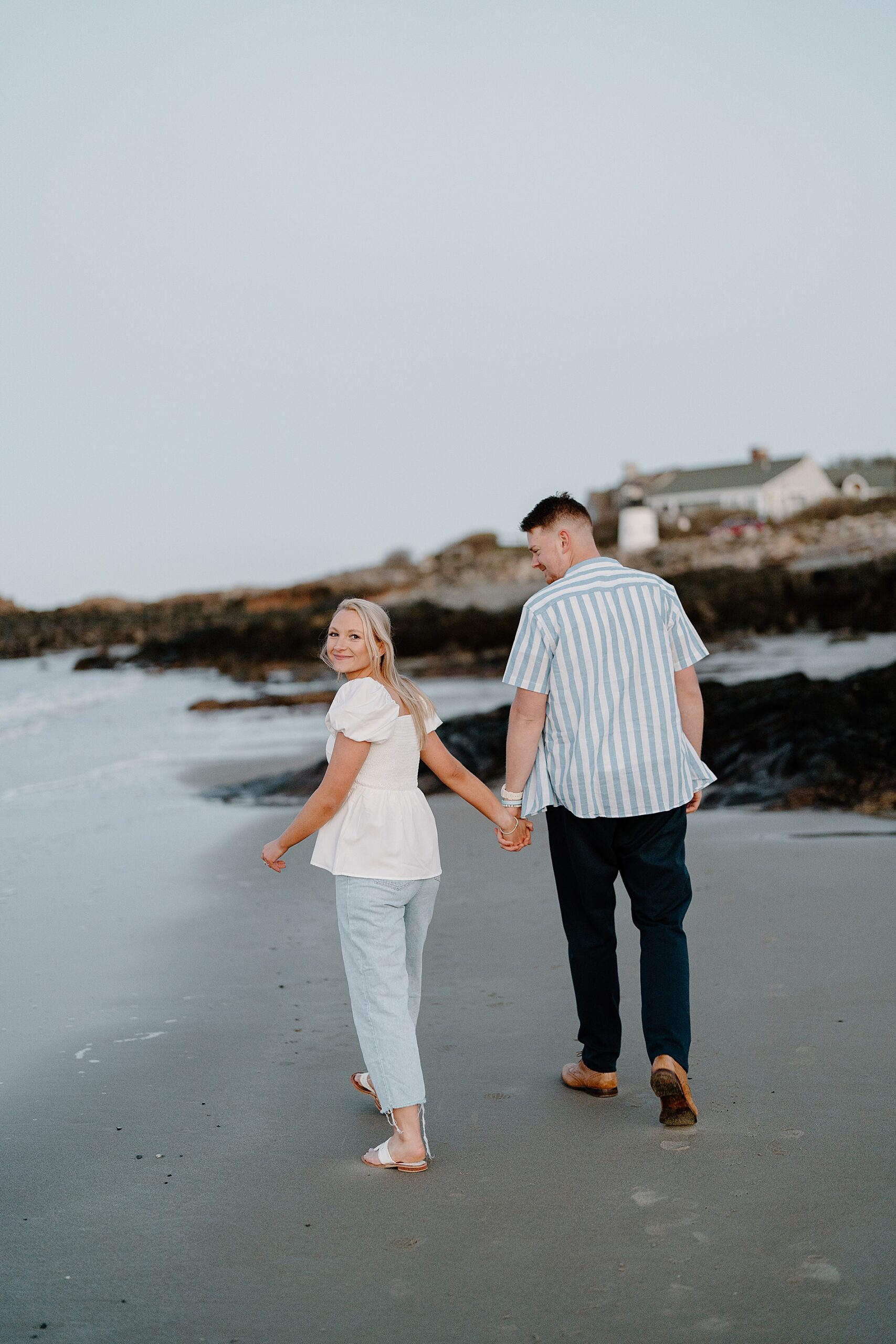 couple walk the beach in Maine during engagement session