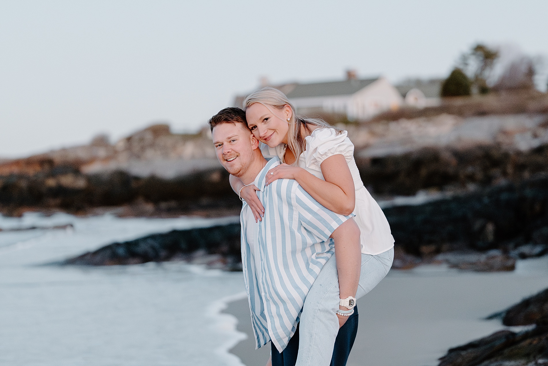 guy carries his fiancé on back on the beach