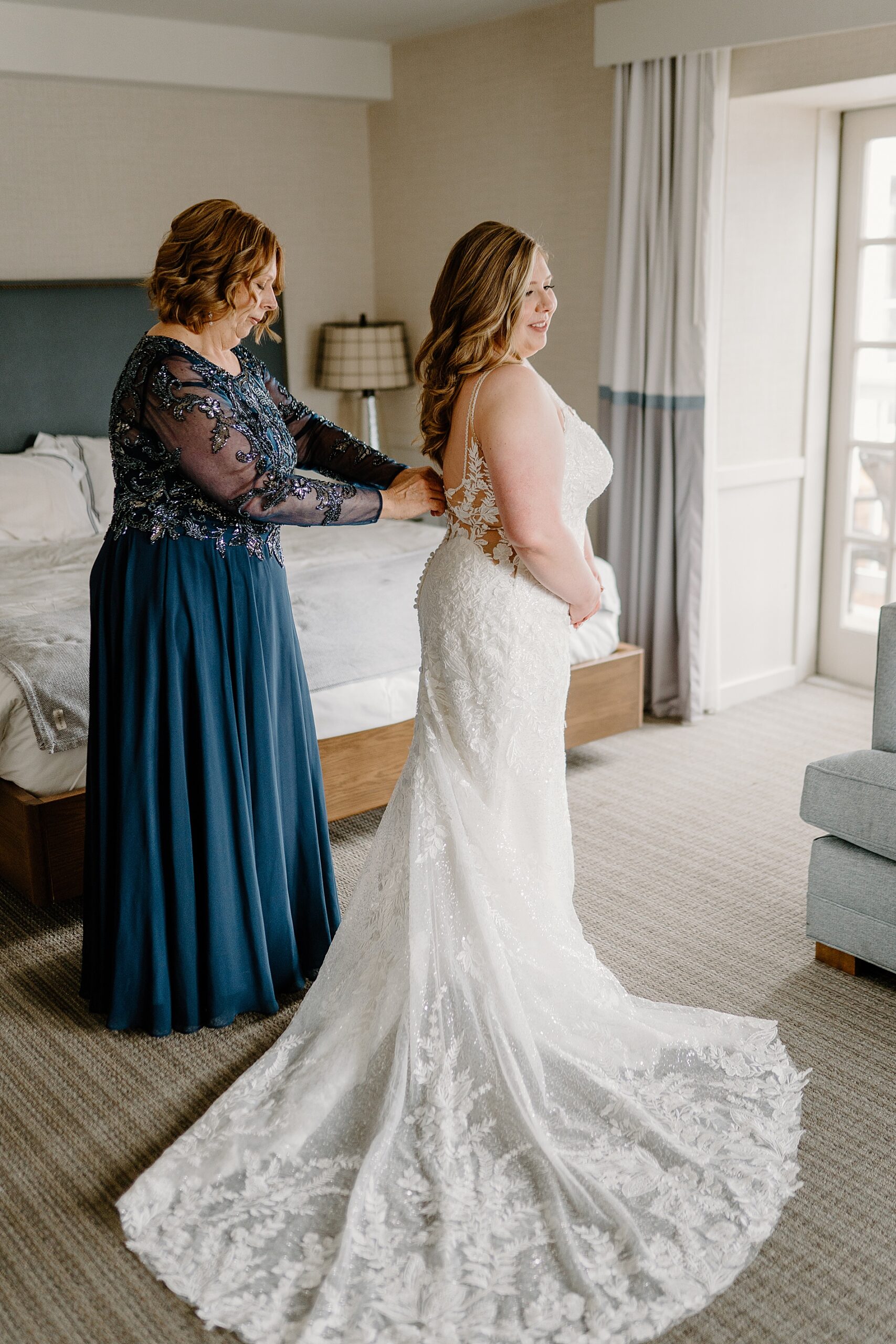 mom helps bride into wedding dress